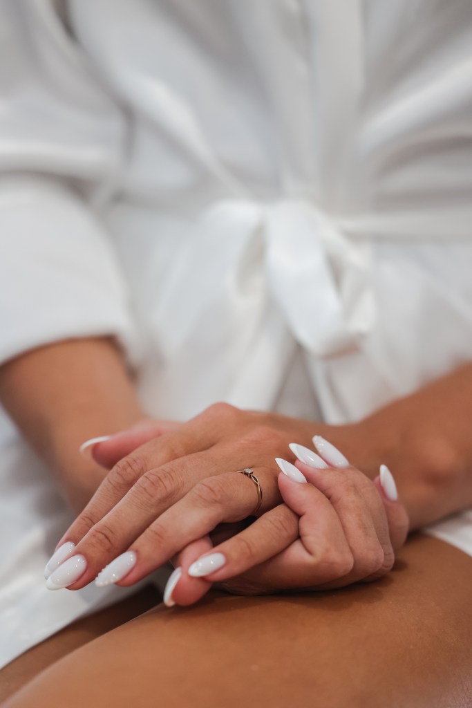Mains de la mariée avec sa bague de fiançailles, en peignoir blanc