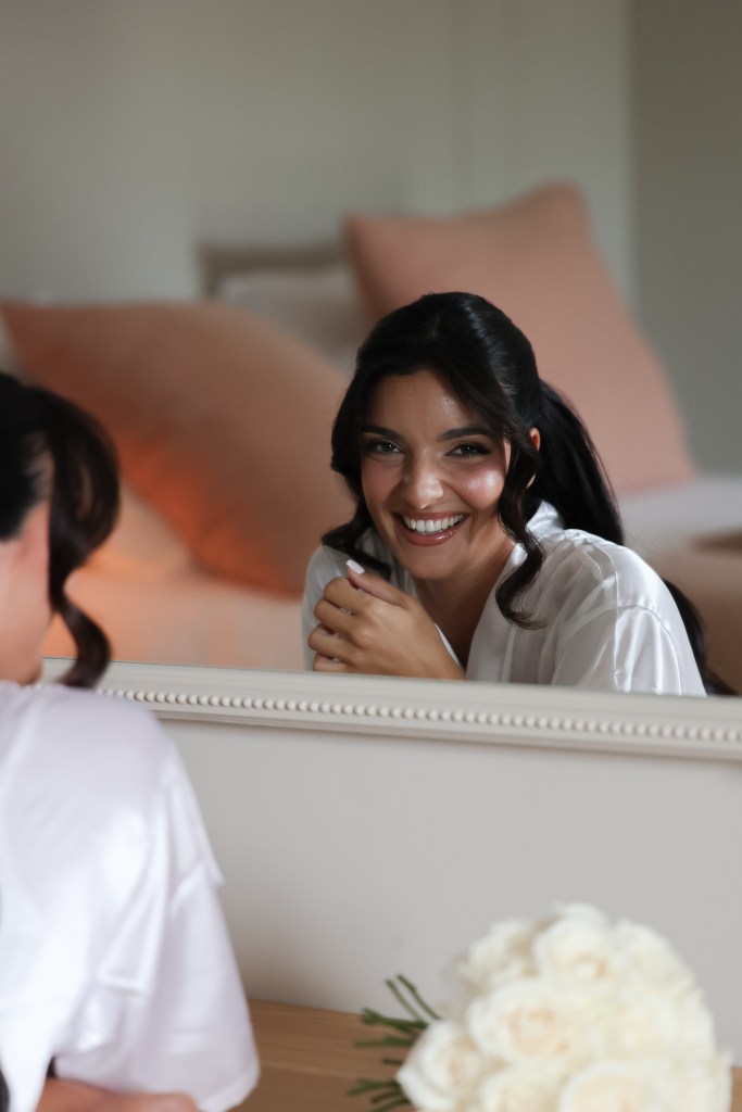 Mariée souriante dans le miroir pendant les préparatifs