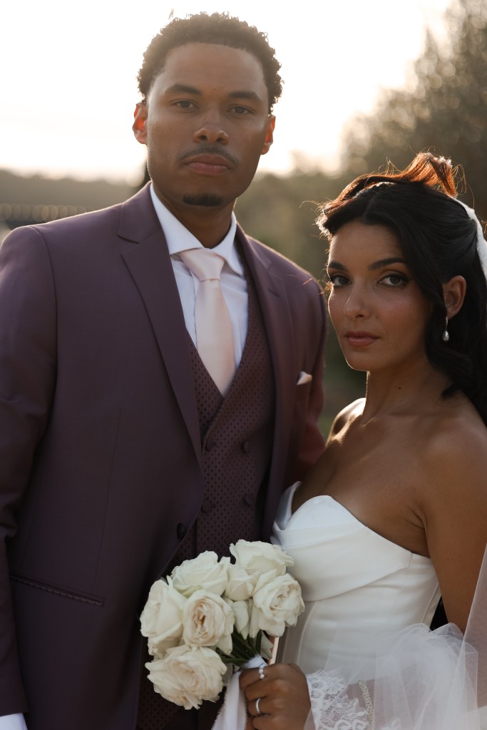 Portrait des mariés en contre-jour avec un bouquet de roses blanches